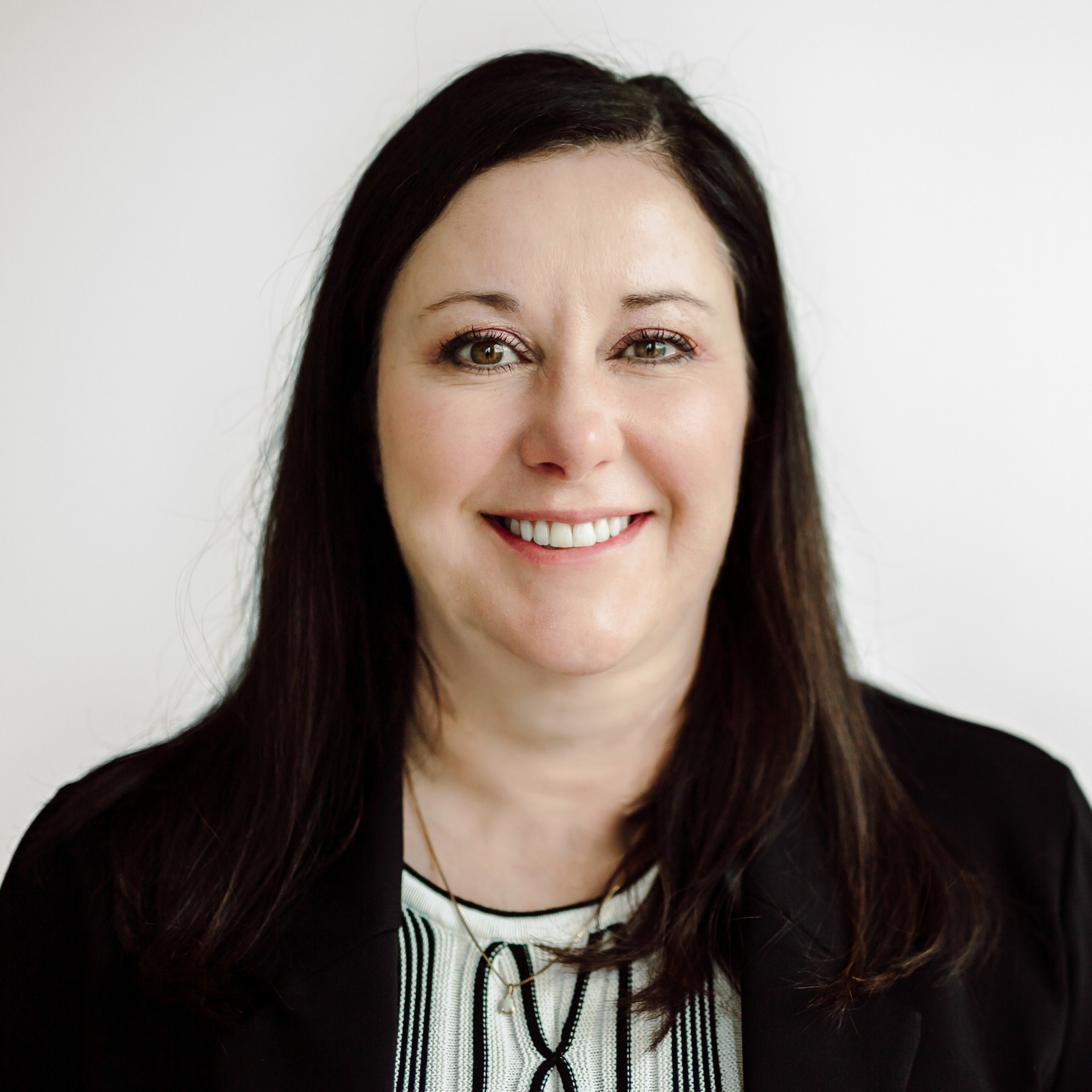 Corporate headshot of a team member with long dark hair in a black blazer