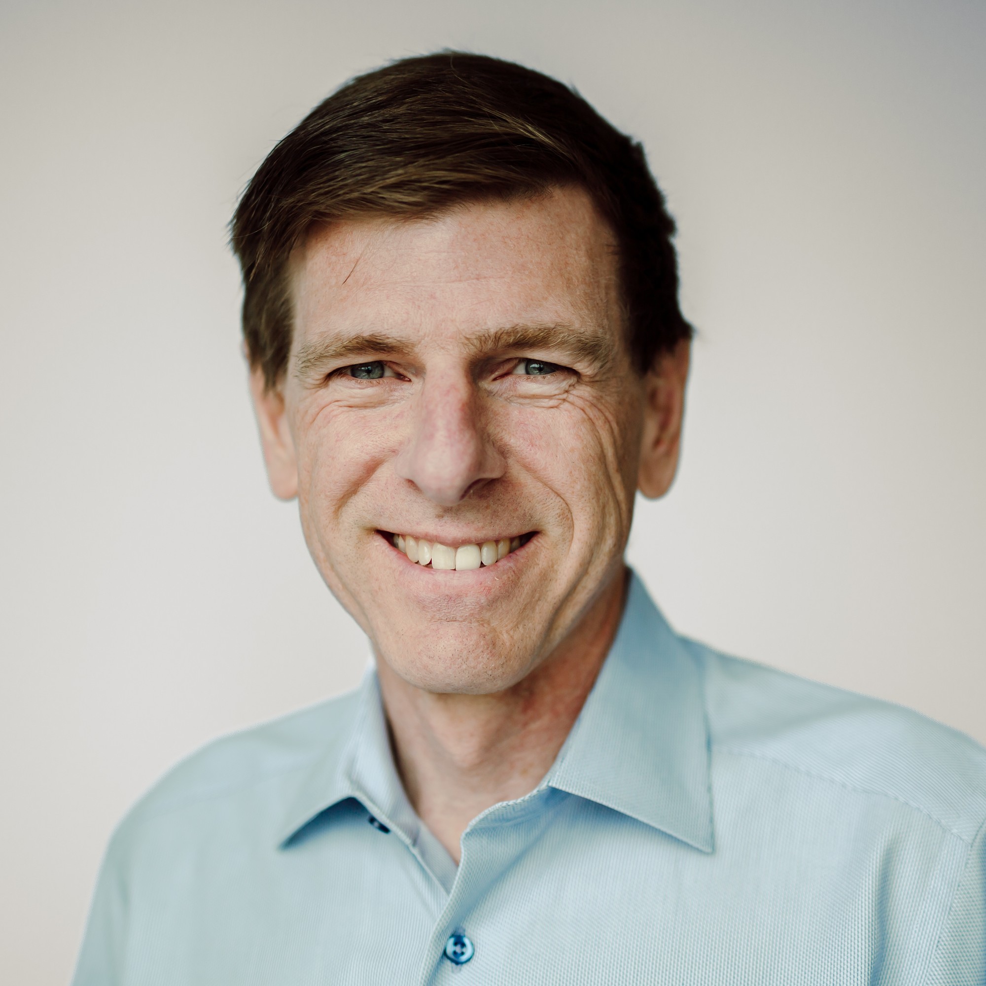 Corporate headshot of a team member in a light blue button-down shirt