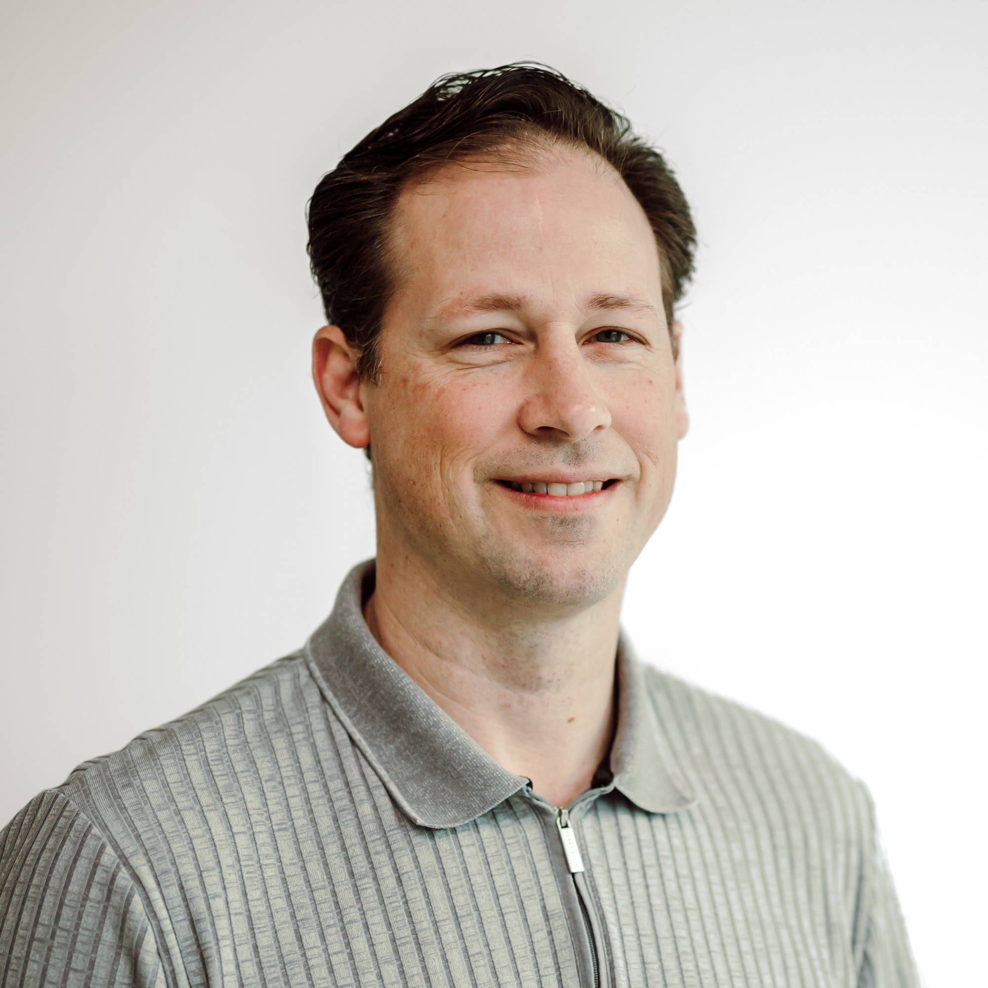 Corporate headshot of a team member in a grey collared zip shirt