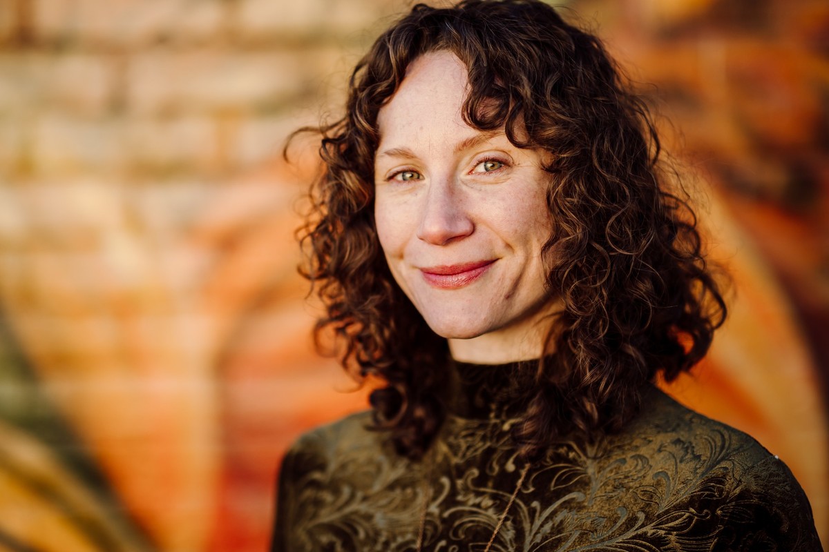 The same client in warm golden light against an orange brick wall