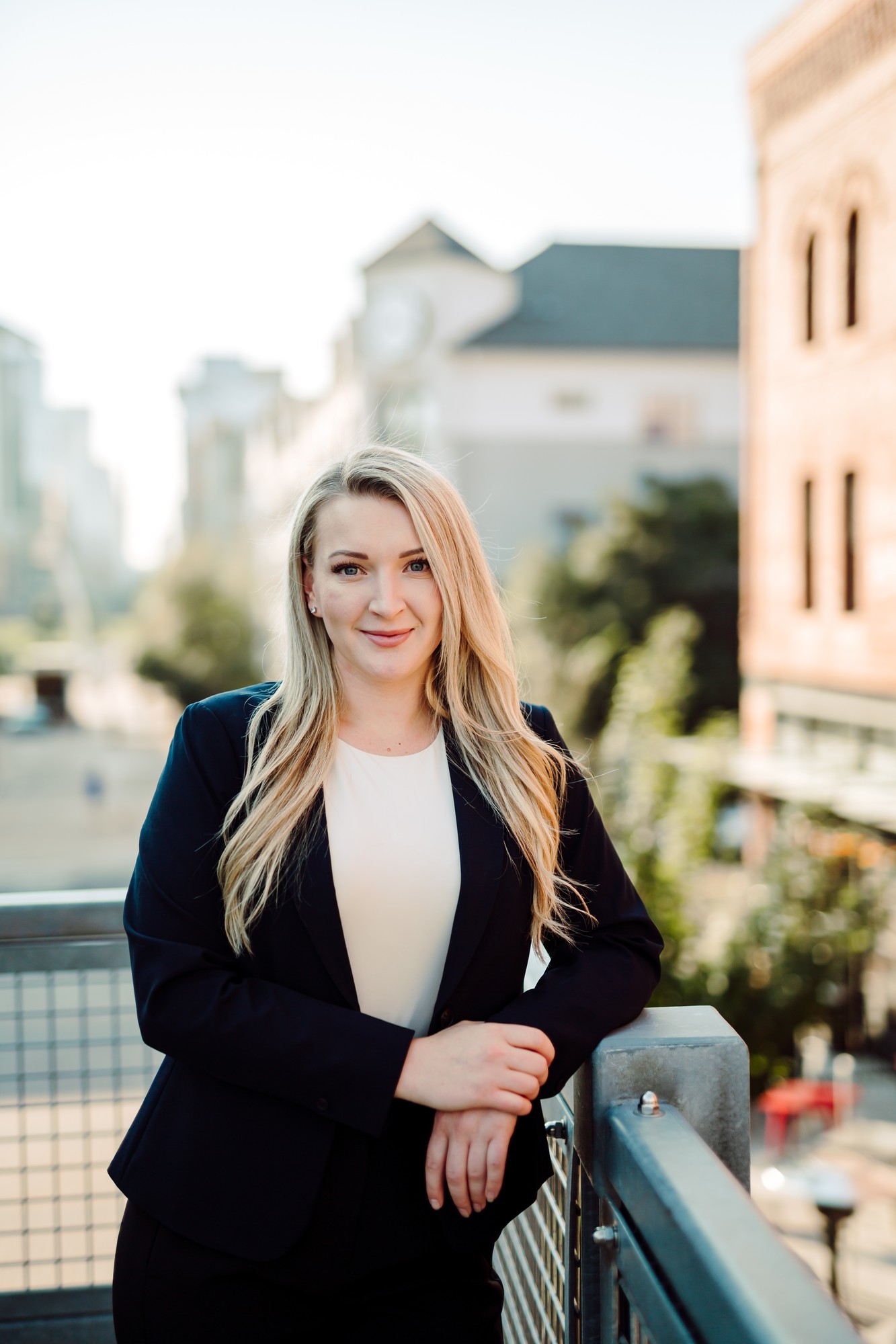 Headshot client in a navy blazer leaning on a railing above a downtown street